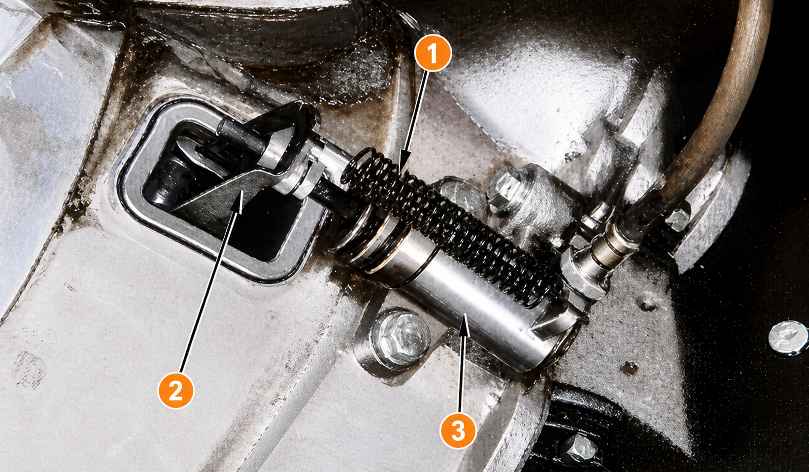 Operating cylinder installed on the clutch housing, showing the return spring, withdrawal lever, and push rod relationship
